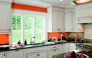 a kitchen with white cabinets and orange walls