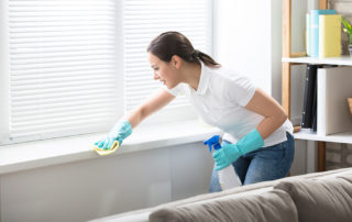 a woman in white shirt and blue gloves cleaning window