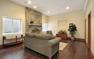 a living room with a stone fireplace and wood floors