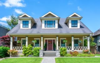 The front exterior of a home with many plants and a green yard