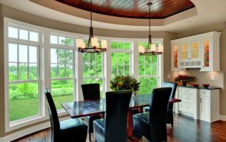 a dining room table with black chairs and windows