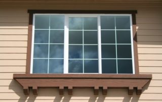 A window with brown wood trim and the beige exterior of a house