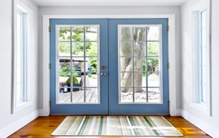 a blue front door with two windows and a rug on the floor