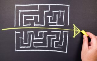 A maze is hand-drawn on a chalkboard, with a straight line running from one side to the other.